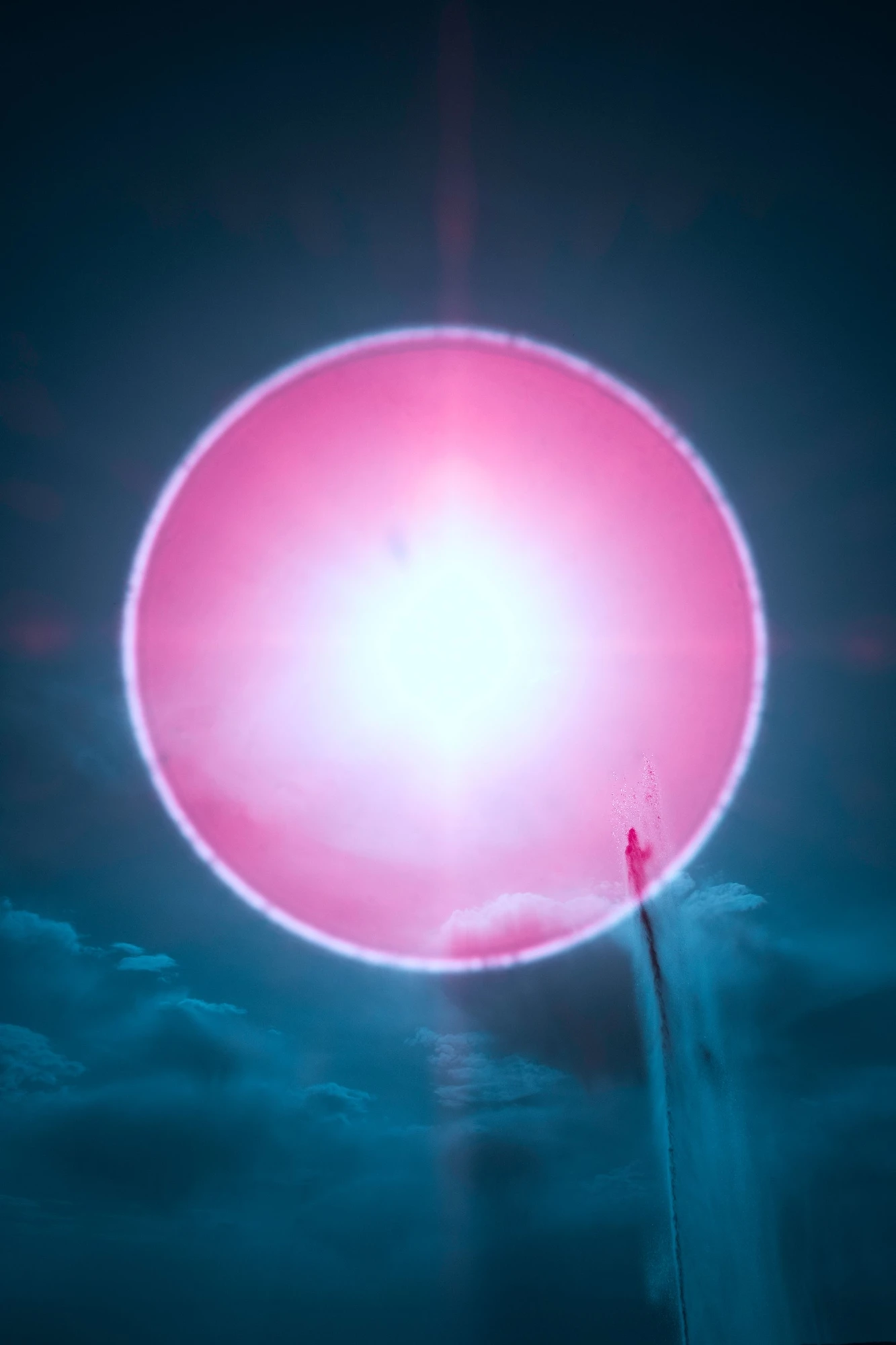 Infrared fine art photography by Andr&eacute; Wagner: A luminous pink circle occupies almost the entire width of the dark vertical frame &mdash; SUN HALO AND FOUNTAIN.