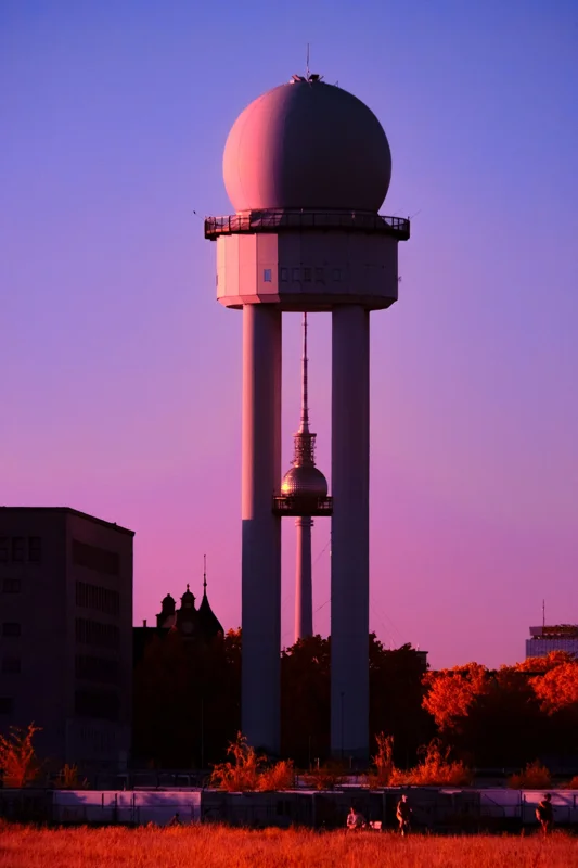 Photographie d’art infrarouge d’André Wagner: Une tour à sommet sphérique se dresse, imposante, devant un ciel rose-violet — Tempelhof Perspective.
