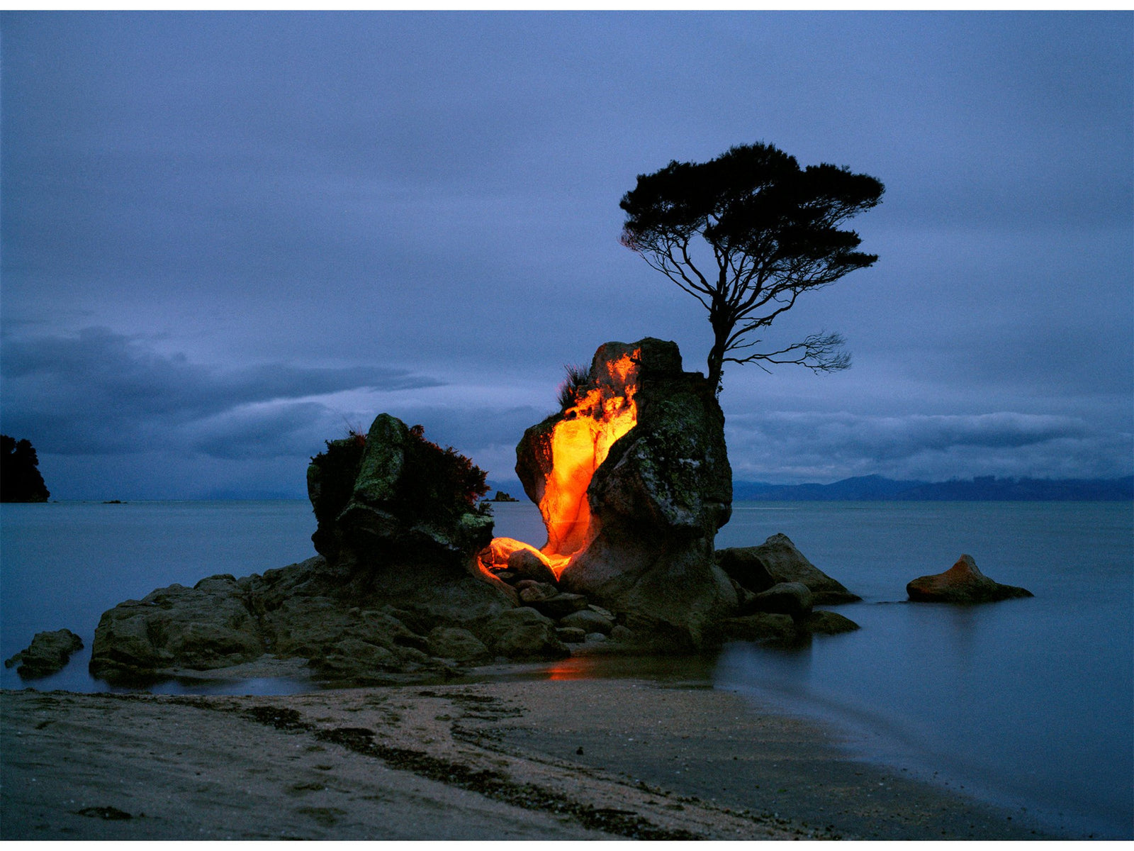 Fine art photography by Andr&eacute; Wagner: A small rock supporting a tree stands near the shore &mdash; To play with fire, Neuseeland.