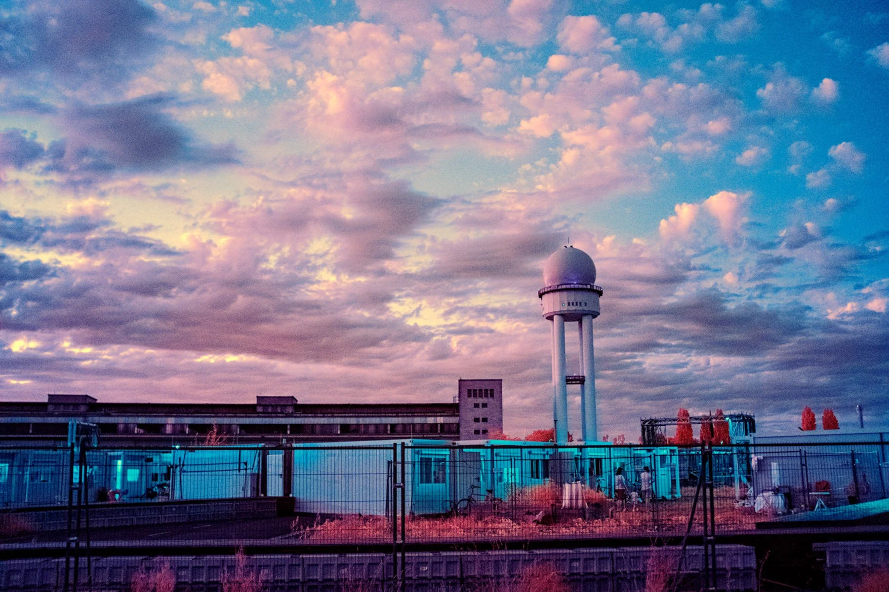 Tour au-dessus de bâtiments bas sous un ciel aux nuages colorés.