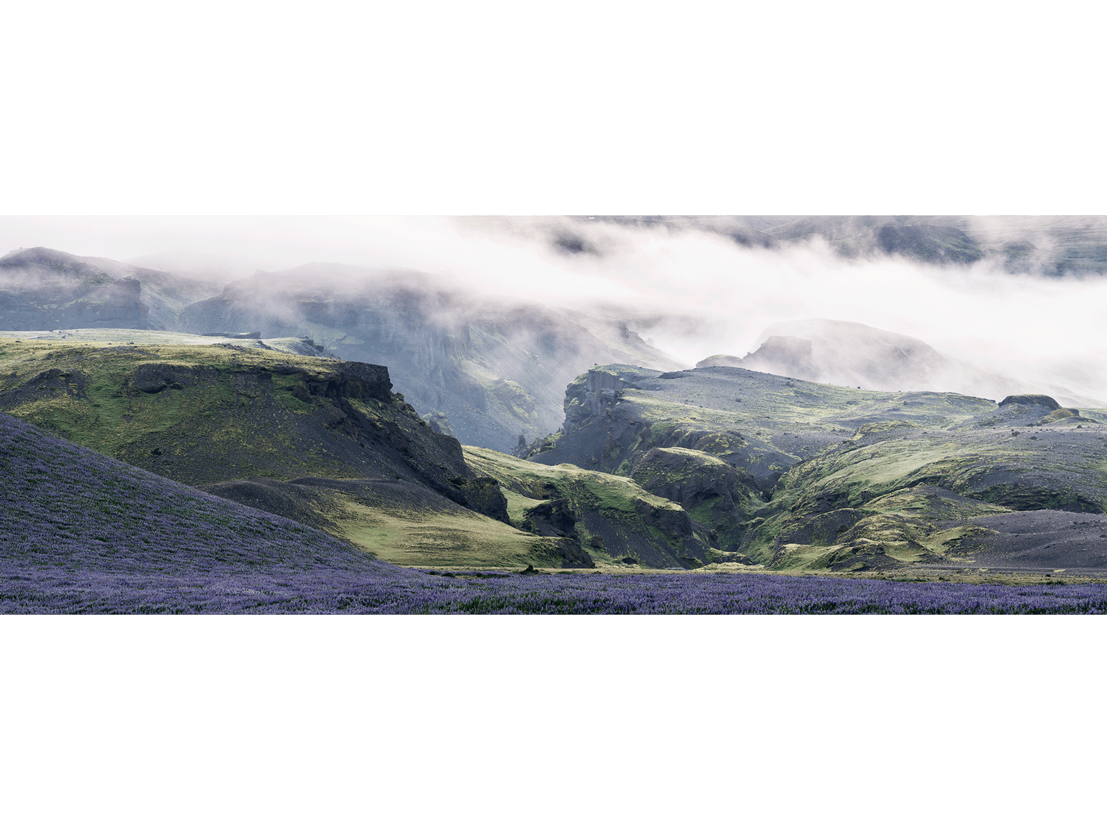 Photographie d’art d’André Wagner: Des versants sombres et des creux verdoyants parcourent un long panorama — Unreal midnightsun in the mountains 1, Island.