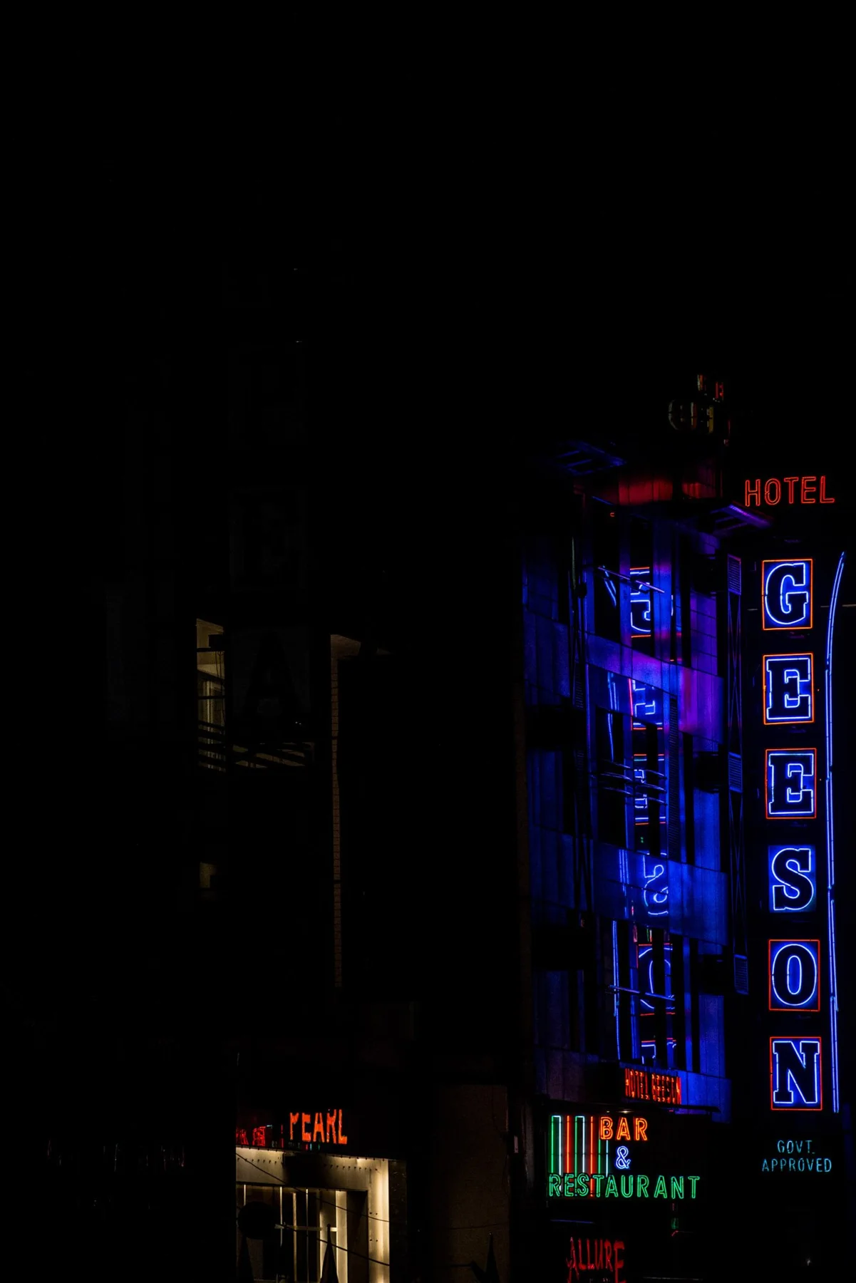 Vertical illuminated signs and headlamps in a night street.