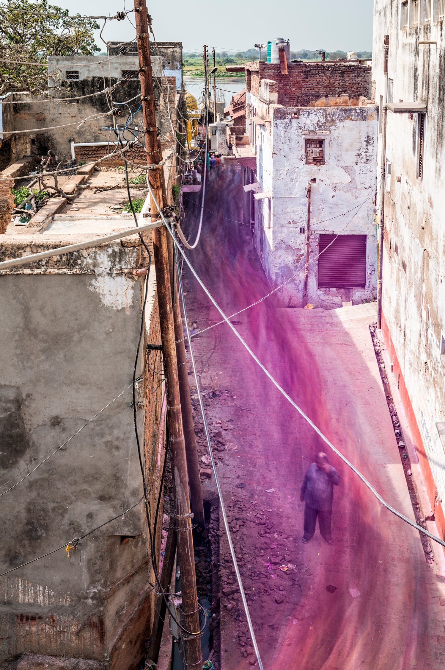Photographie d’art d’André Wagner: Une ruelle étroite s’enfonce entre des murs de maisons clairs — Vrindavan flow, Indien.