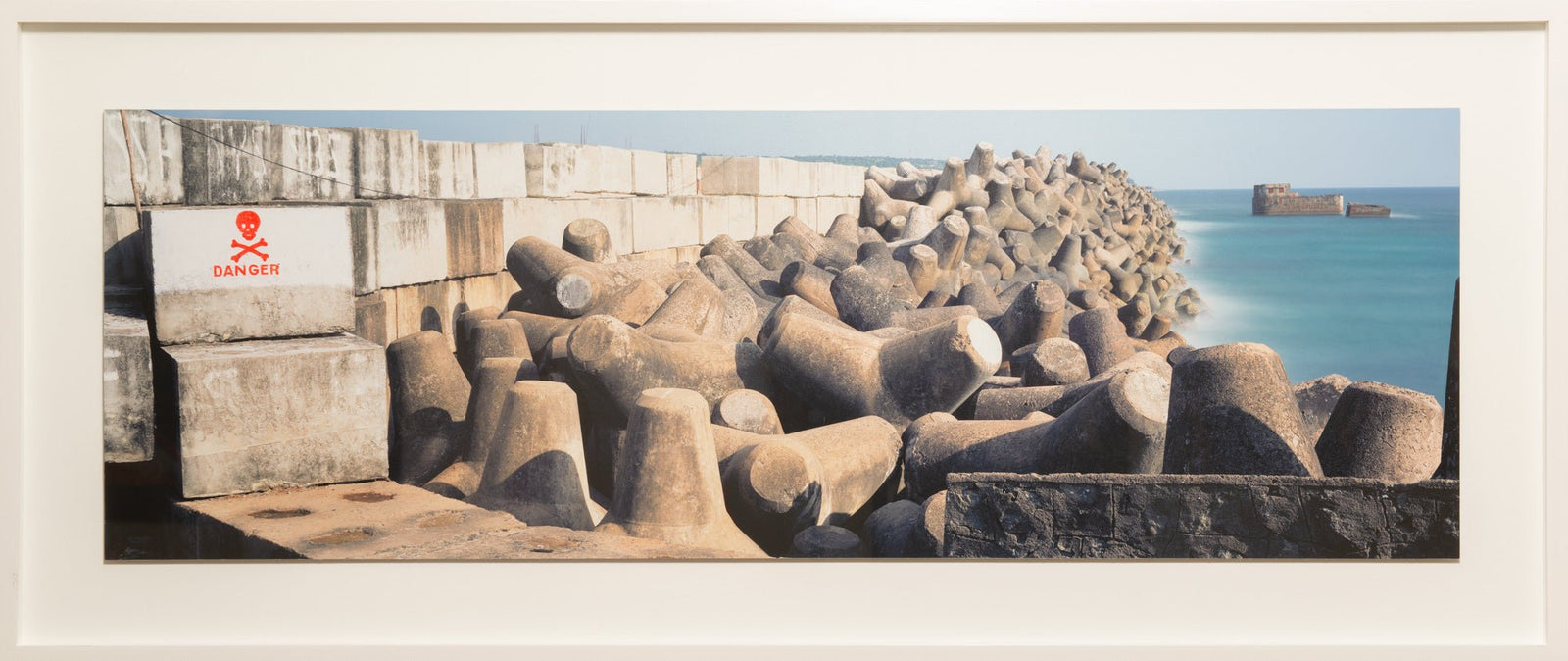 Fine art photography by André Wagner: Massive multi-armed concrete forms lie packed along a coast — Wave Breakers, Indien.