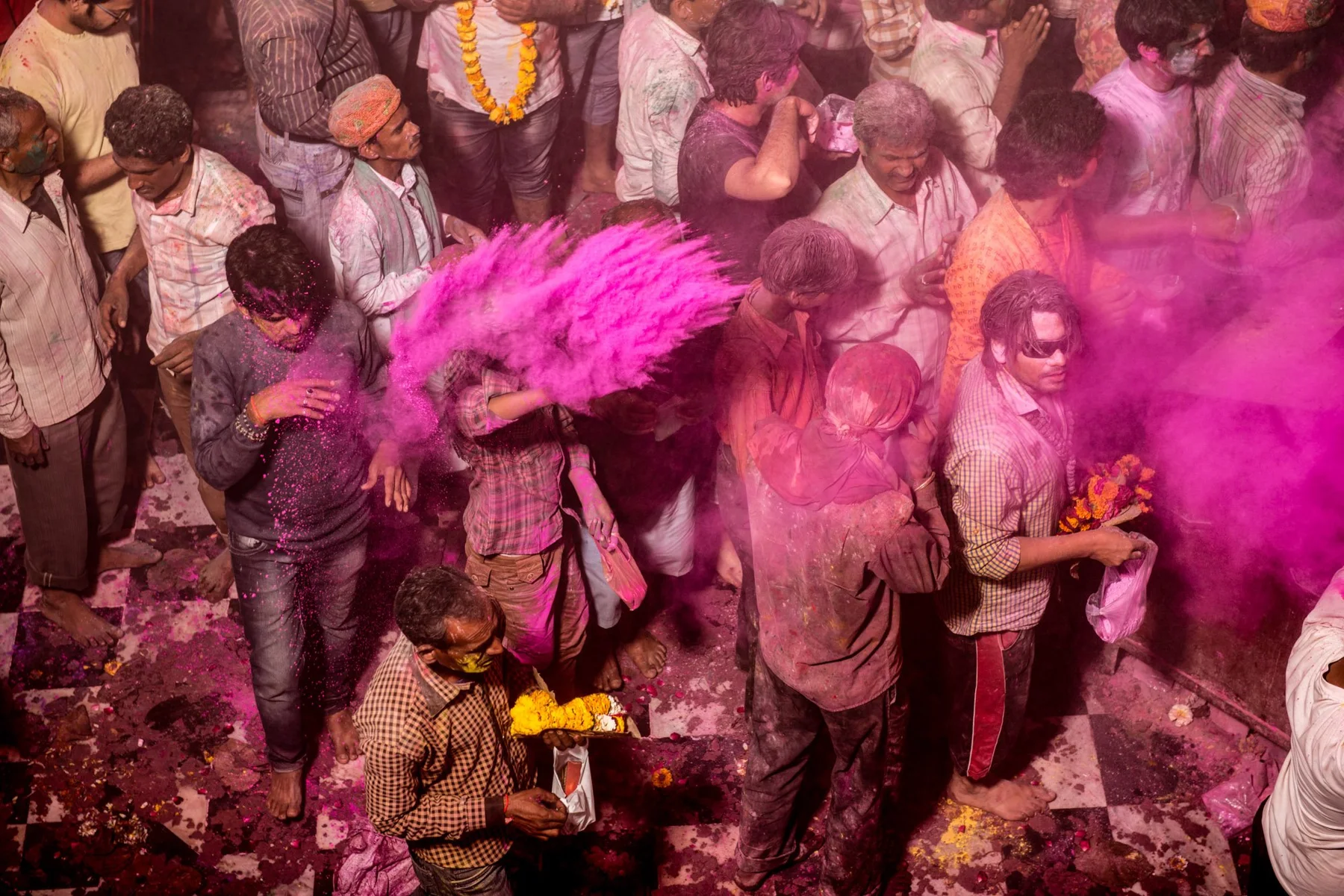 Des personnes célébrant Holi sous un nuage de poudre rose.