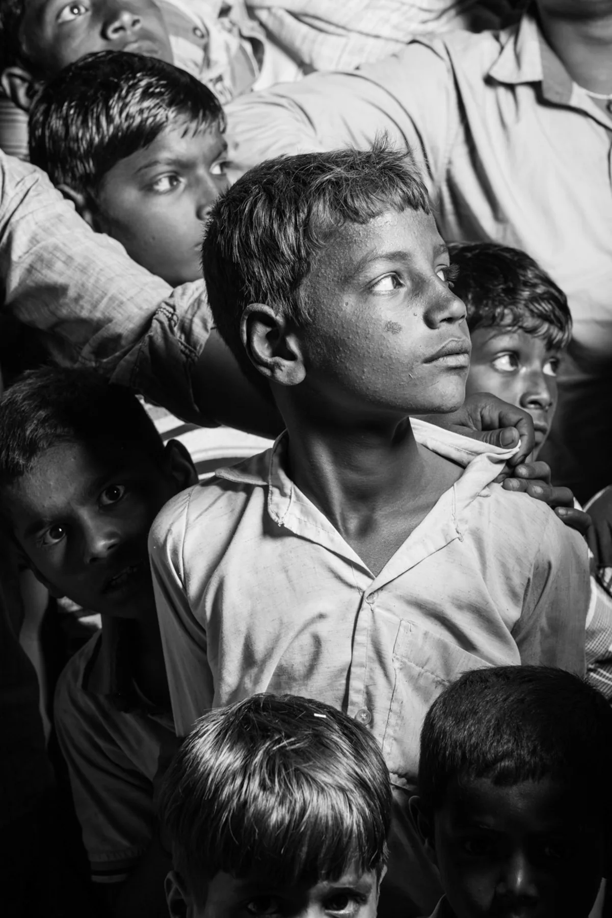 Portrait en noir et blanc d’un garçon au milieu d’une foule.