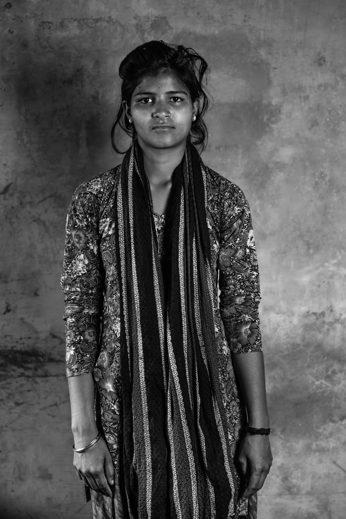 Portrait en noir et blanc d’une jeune personne portant une longue étoffe à motifs.