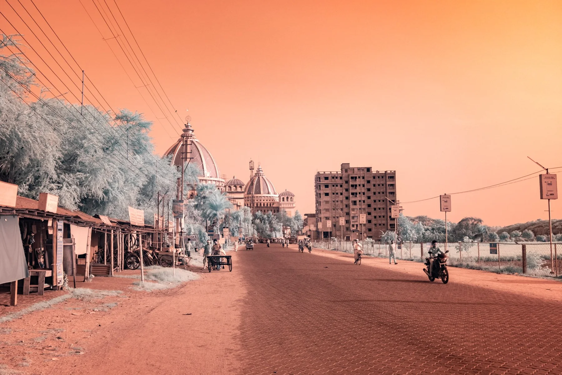 Street with temple towers and a motorcyclist.