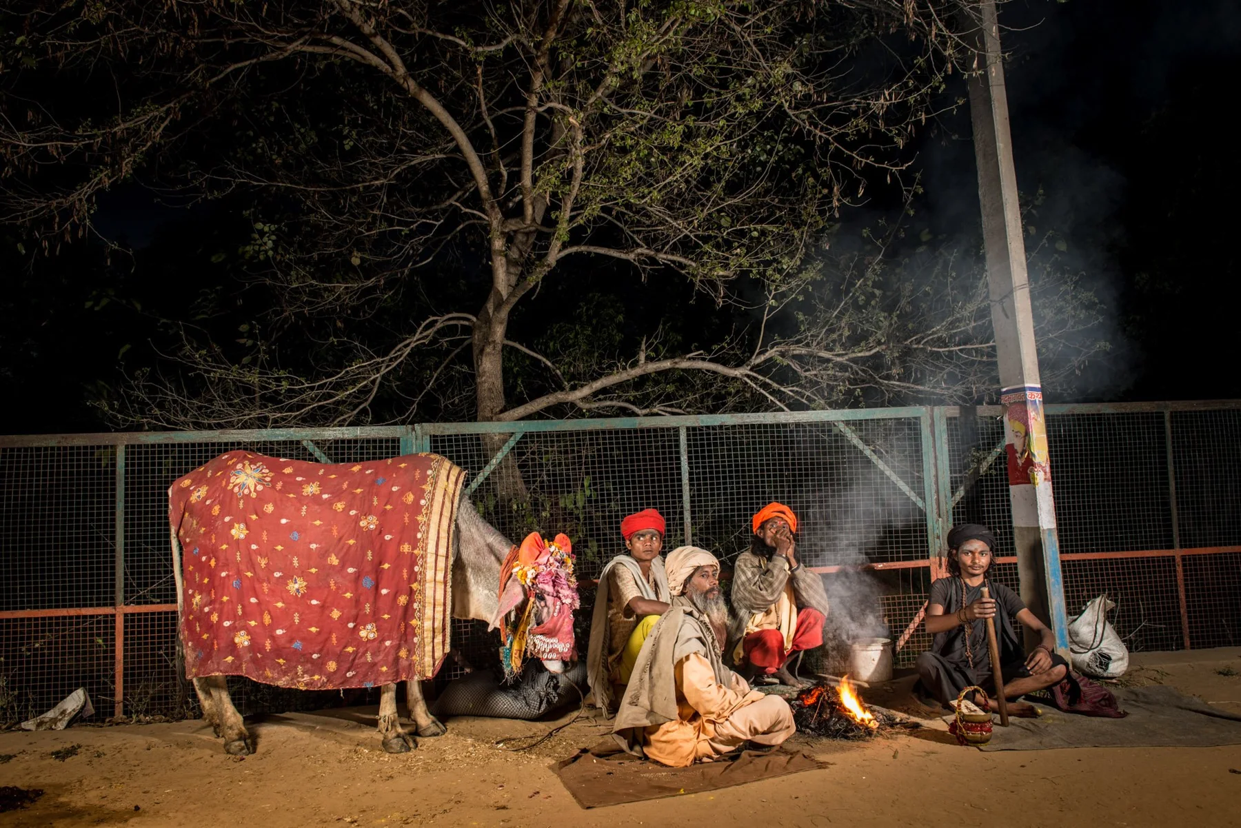 Marchands de rue et charrettes de marchandises sous un arbre, la nuit.