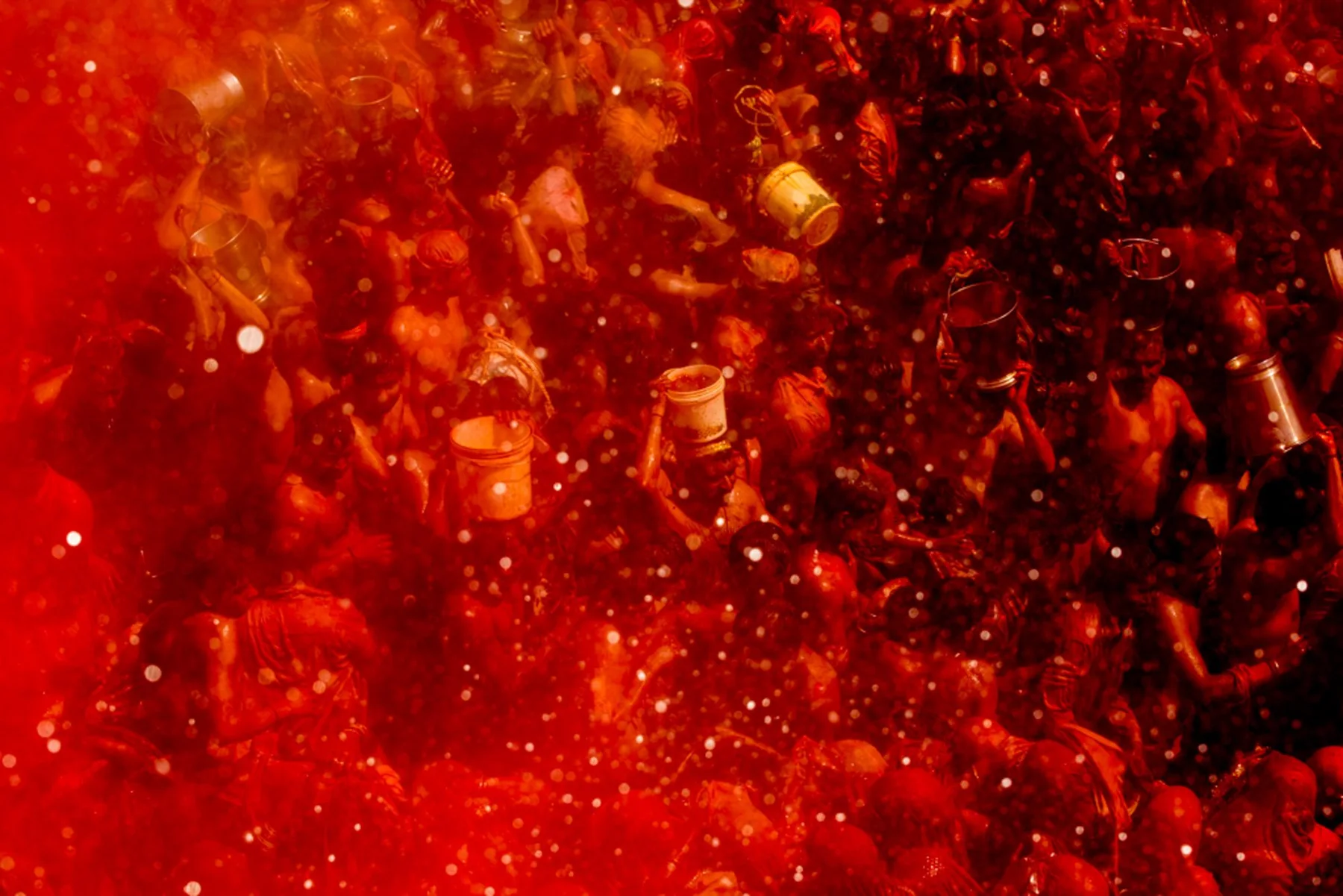 Vue d’en haut sur une foule dans un nuage de poudre rouge pendant Holi.