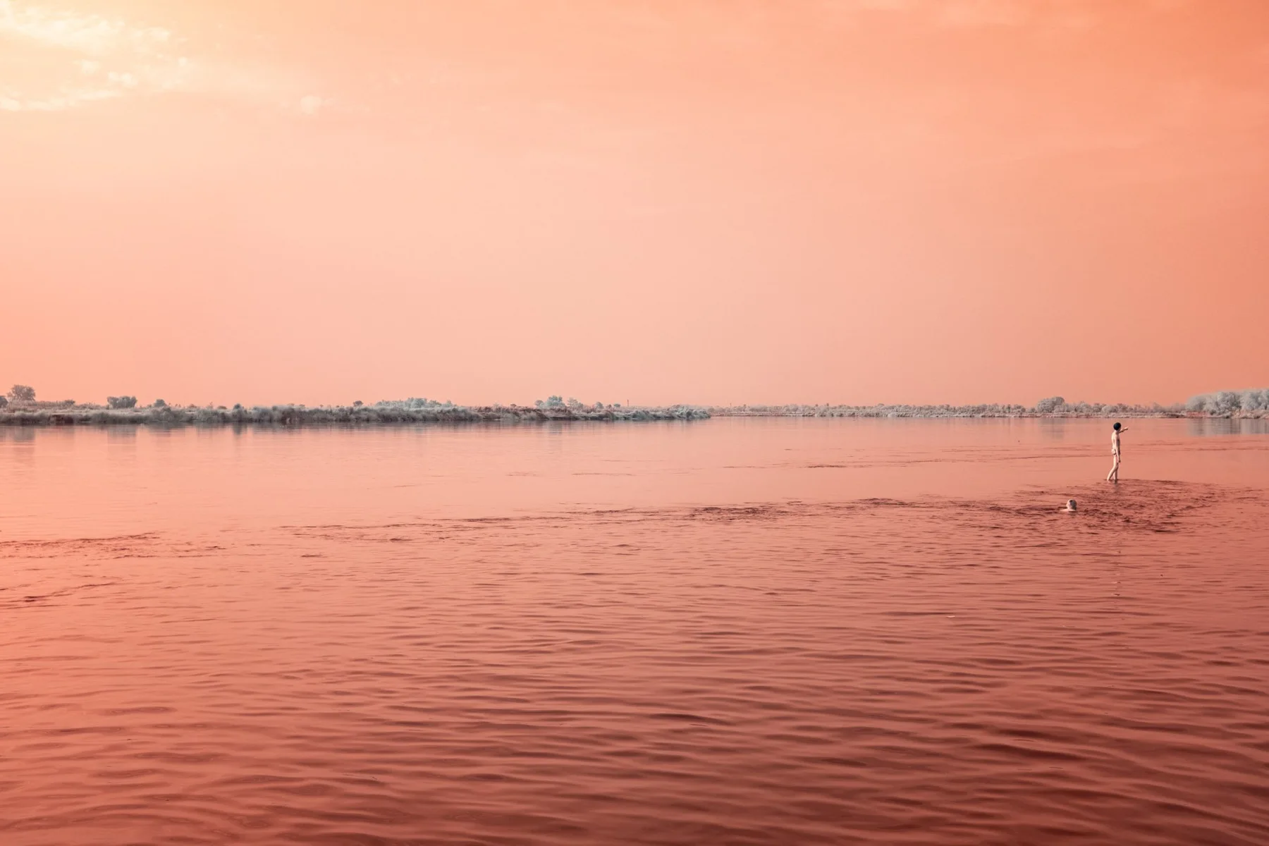 Breiter Fluss unter orangefarbenem Himmel.