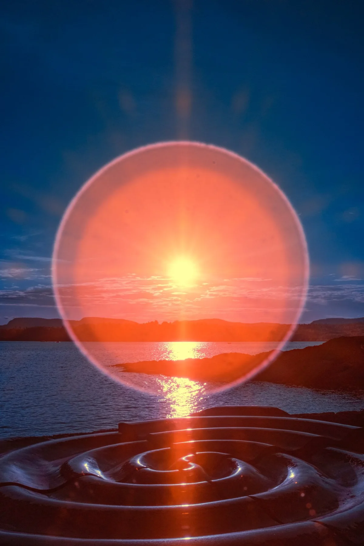 Orange light circle over solar reflexes on the sea.