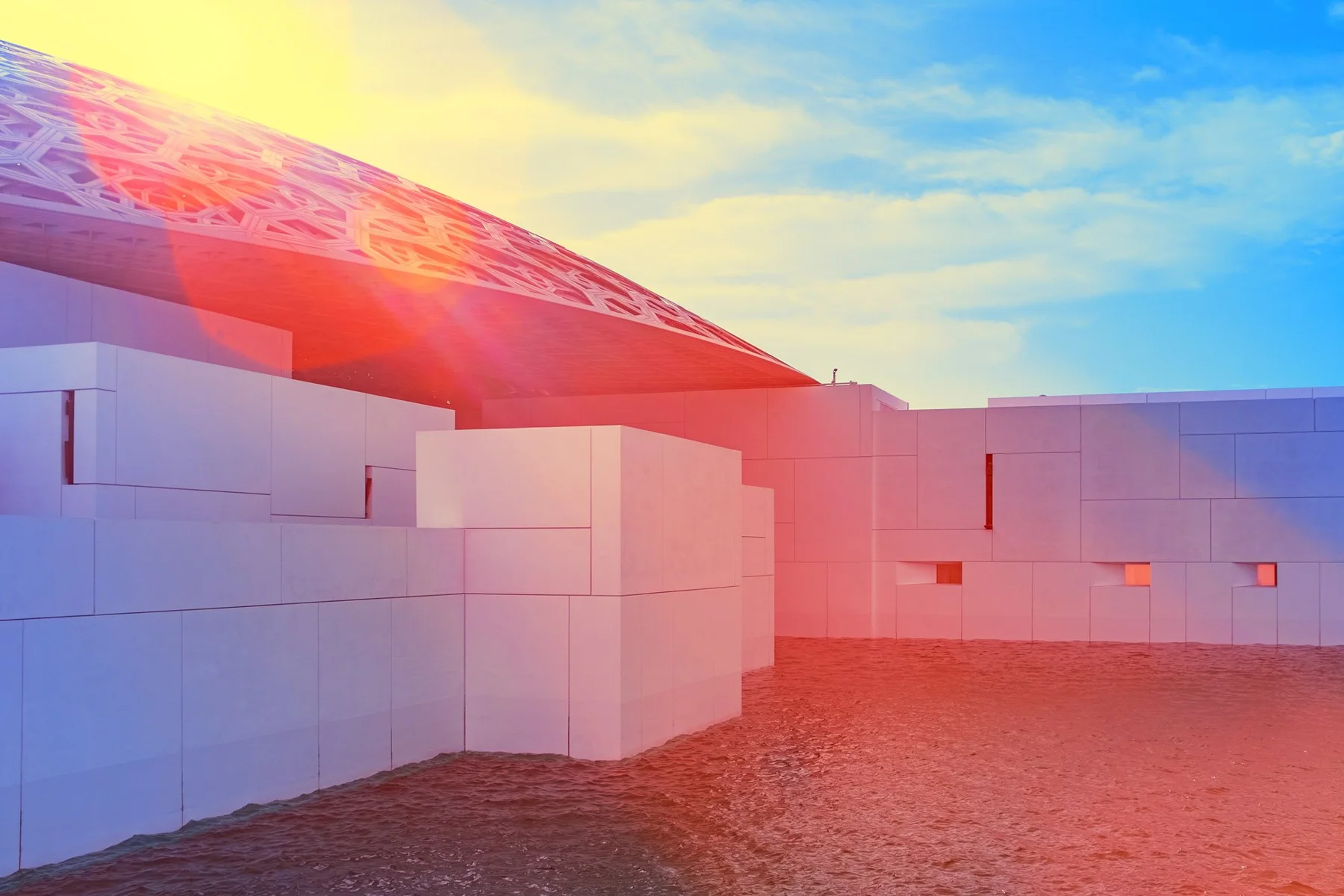 Sun reflexes over white museum buildings on the water.