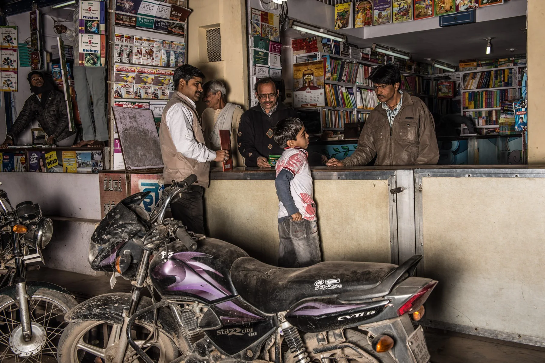 Des personnes près d’un petit kiosque, avec des motos devant, la nuit.