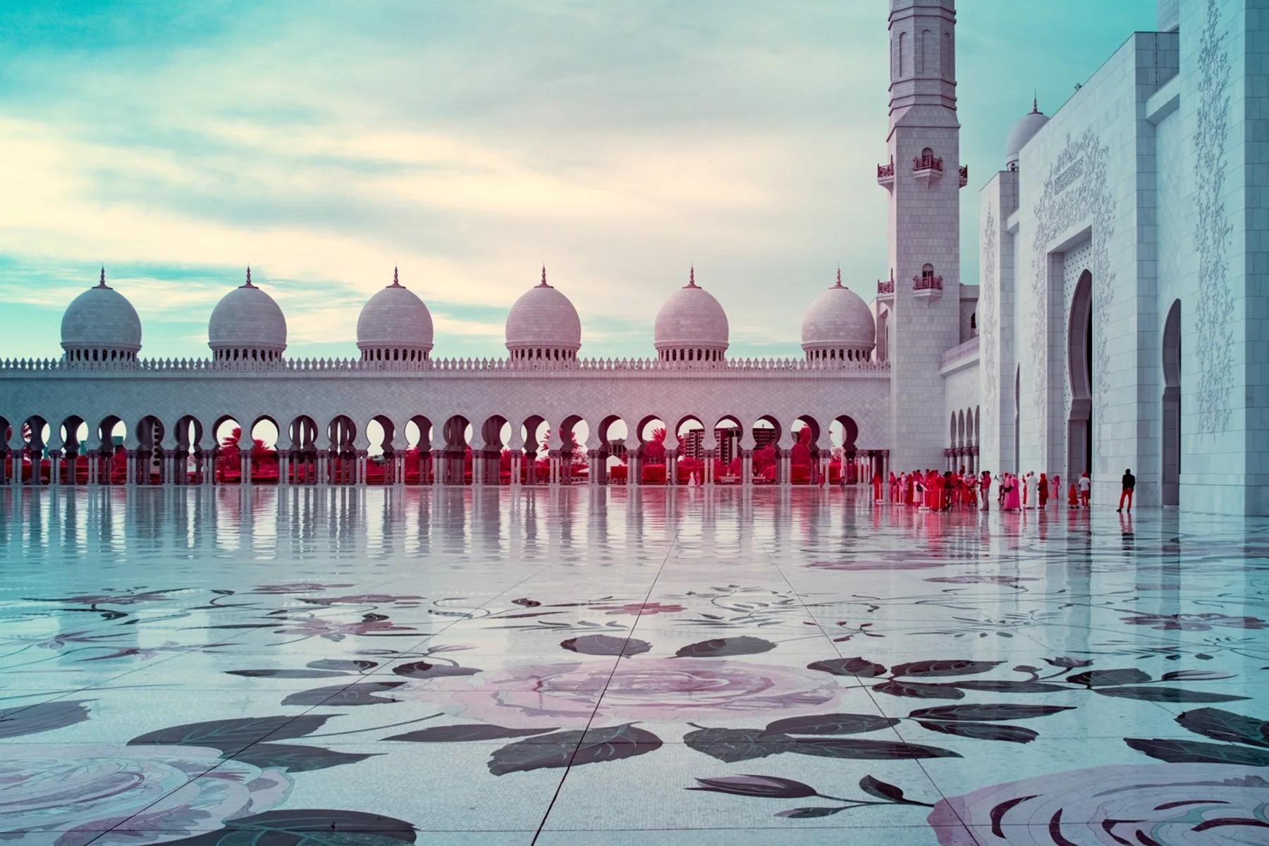 Next mosque courtyard with flower patterns in the ground and a row of domes.