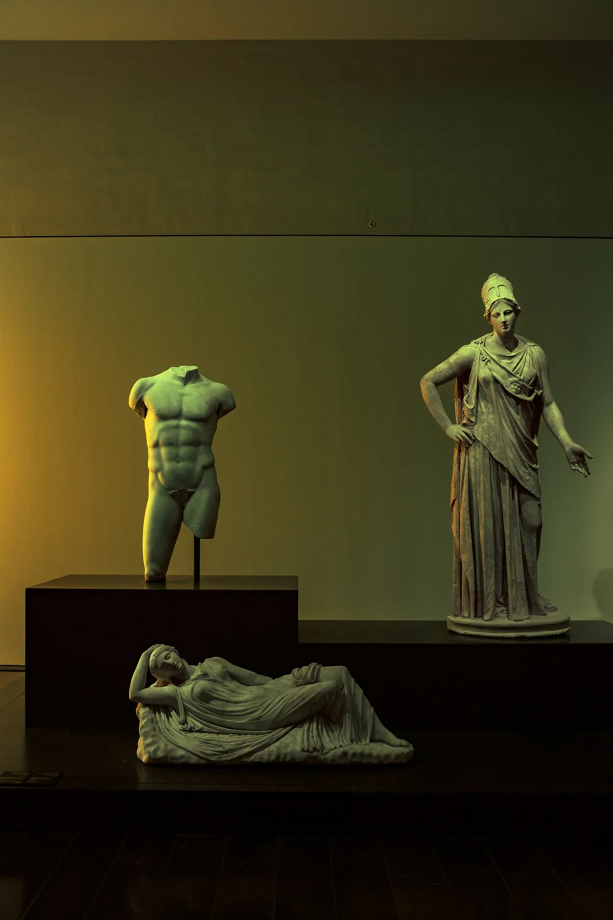 Antike Skulpturen in einem abgedunkelten Ausstellungsraum.
