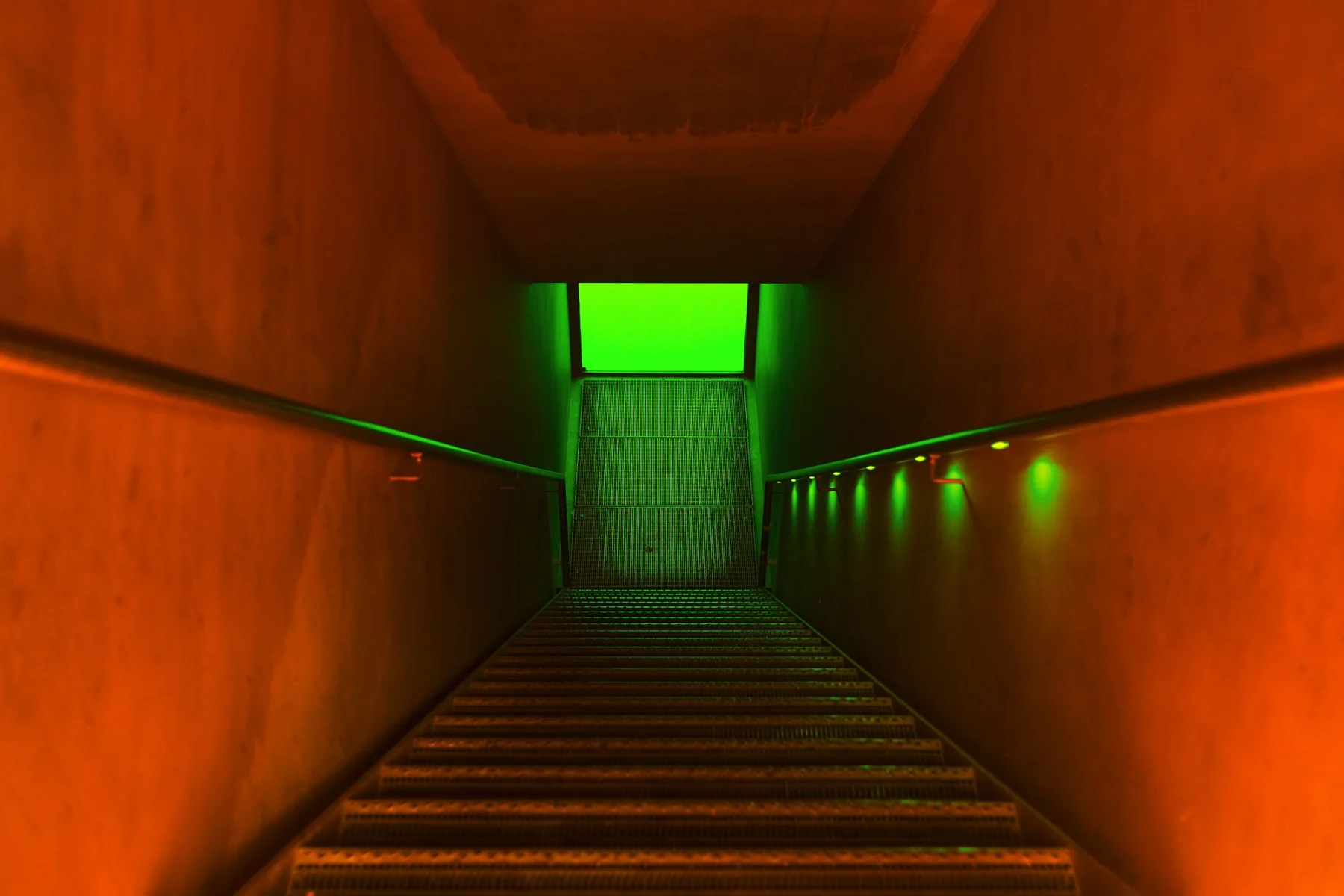 Stairs through an orange corridor to a green glowing door.