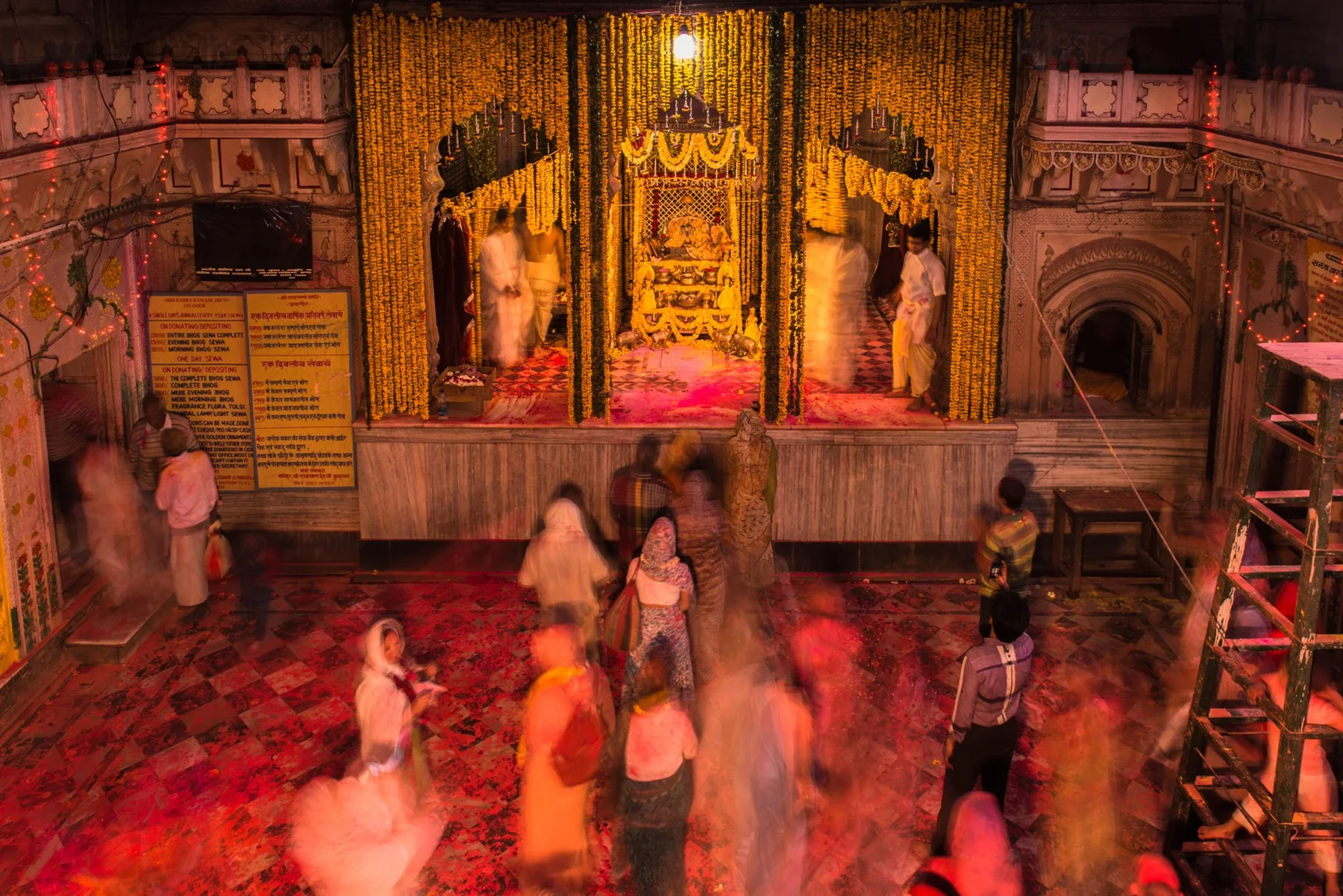 Des personnes dans une salle de temple à la lumière chaude, partiellement floues par la pose longue.