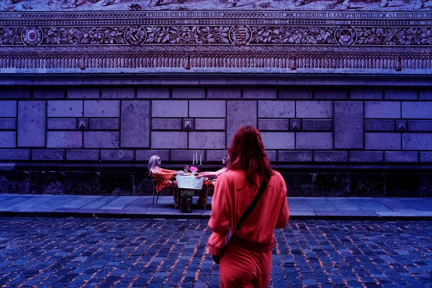 A person observes street musicians in front of a historic facade.
