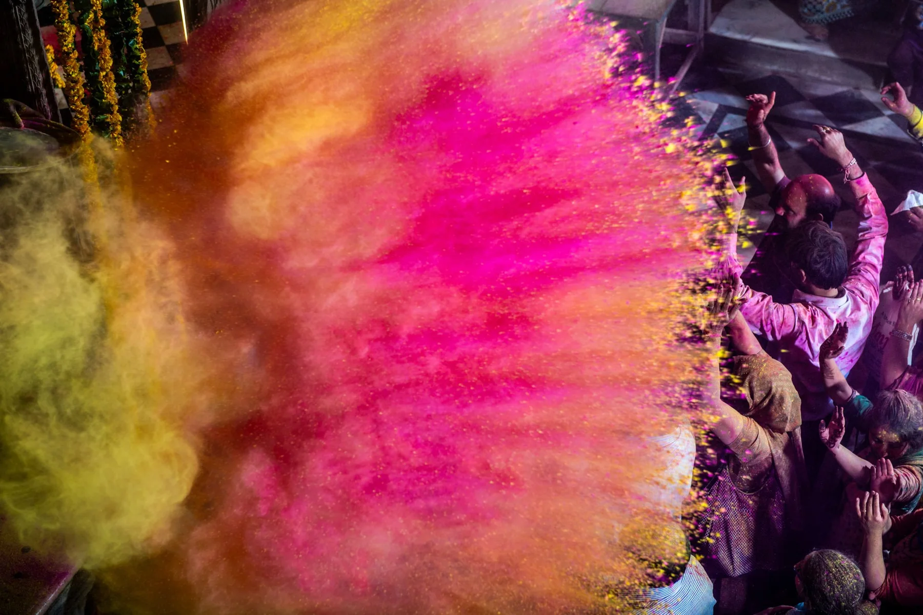 Nuage de poudre rose et jaune au-dessus d’une foule pendant Holi.