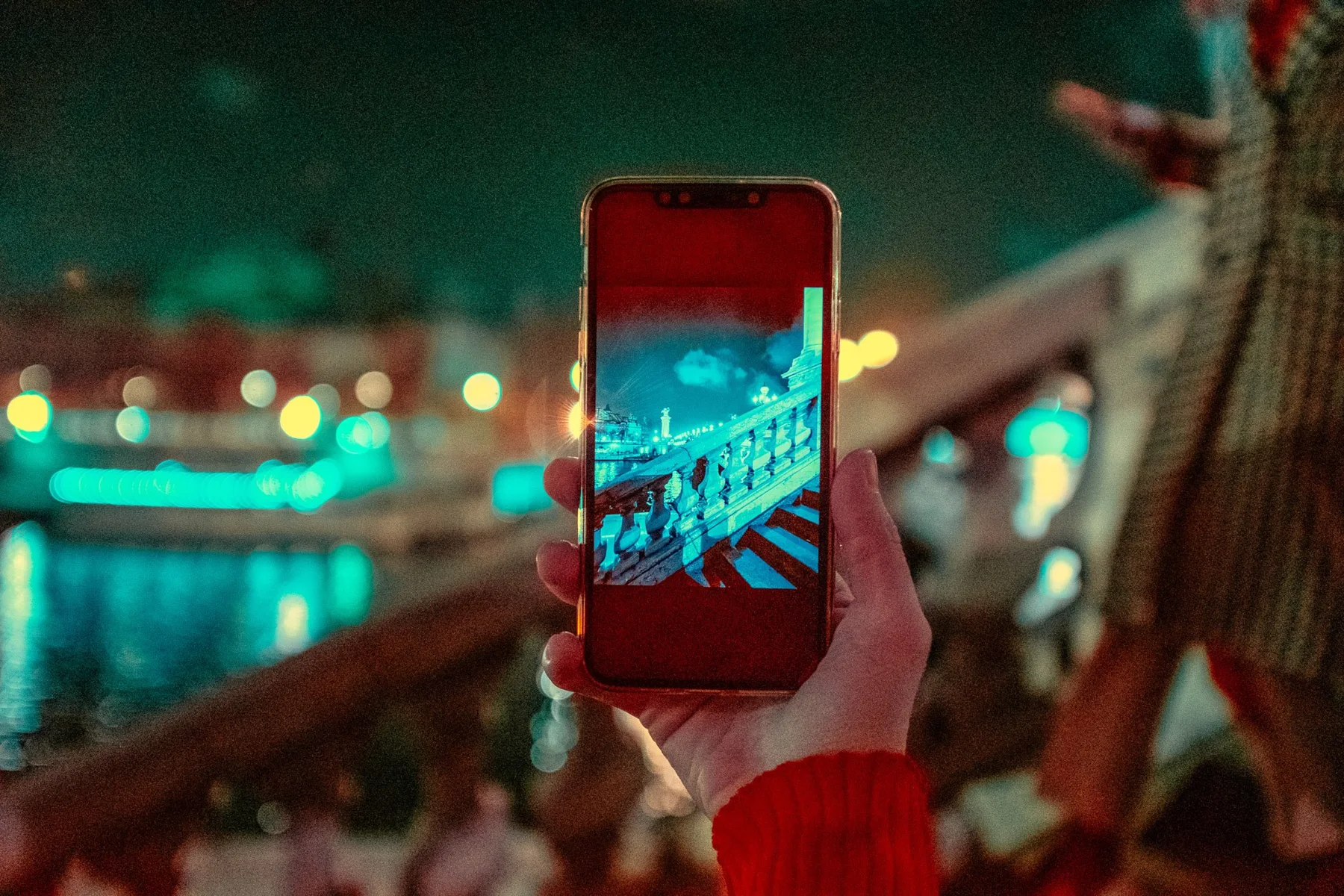A smartphone on the water in front of a night-lit city backdrop.
