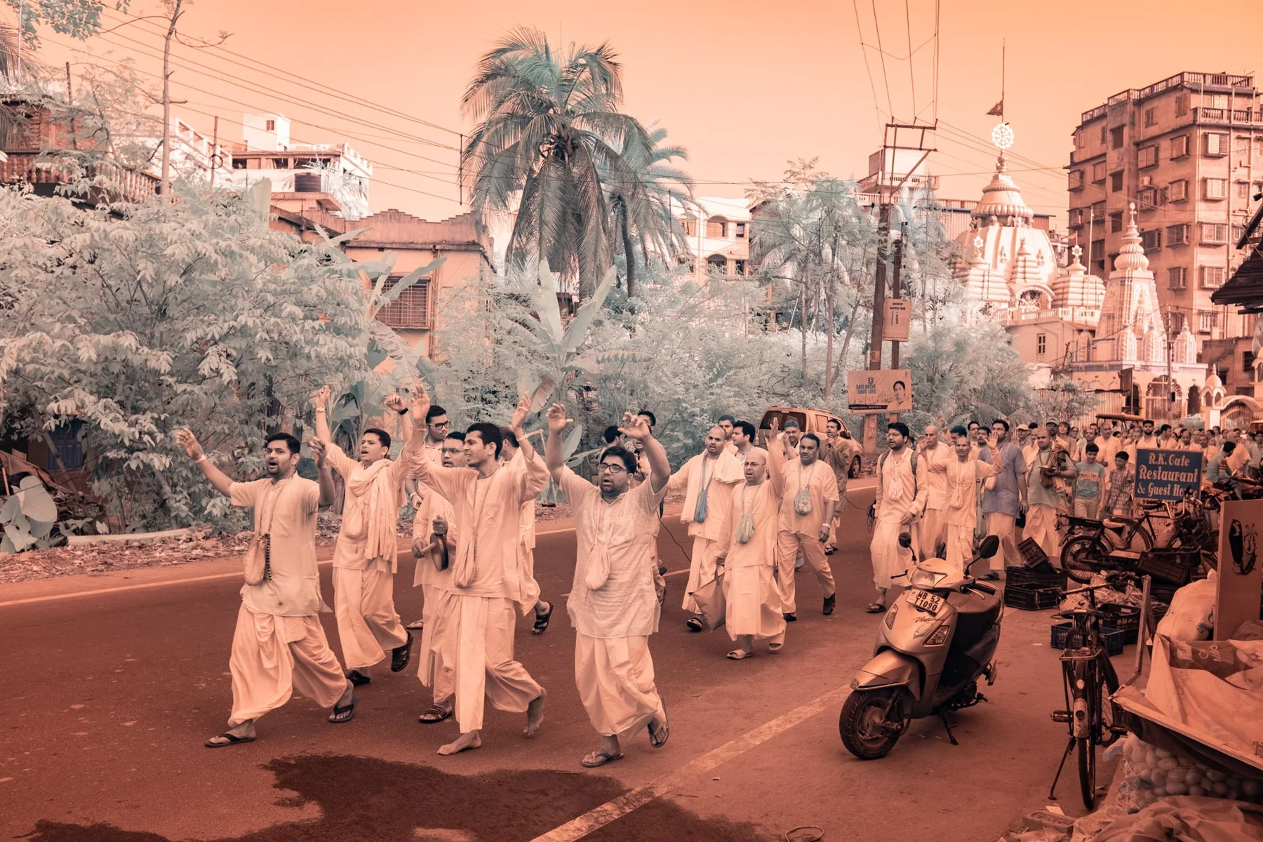 Procession with raised arms on a road with palm trees.